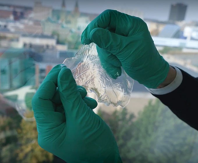 two gloved hands hole a degradable polyester material